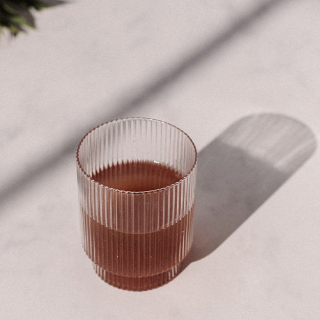 Verre nervuré en verre contenant une une ampoule diluée Cocooning, posé sur une surface claire avec une ombre douce.