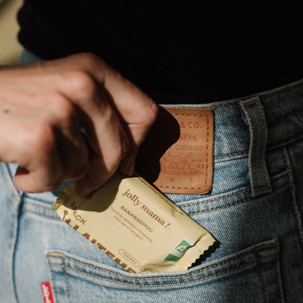 Vrouw die een borstvoeding snack banaan chocolat van Jolly Mama uit haar zak haalt