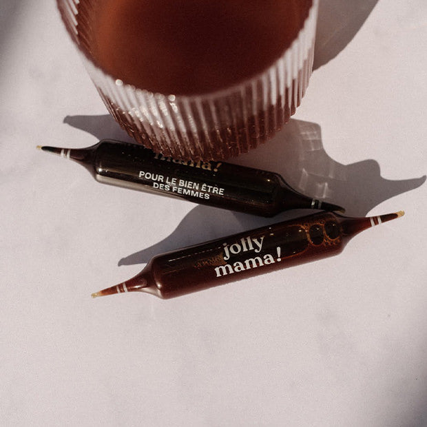 Glass containing the fertility food supplement diluted in a little water, alongside 2 ampoules